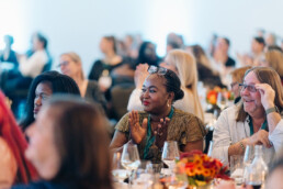 Olabisi Bisira clapping while seated at a table alongside fellow DSP Fellow Scott Robins