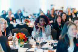 An attendee seated at the Gala with clasped hands propping up her chin