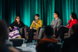 Amber Ward speaking on stage alongside fellow panelists during the caregiving in Indigenous communities plenary