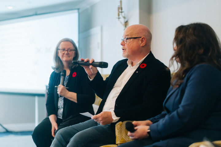 Side profile of Colonel Russell Mann speaking during the military and veteran caregiving panel, with fellow speakers on either side.