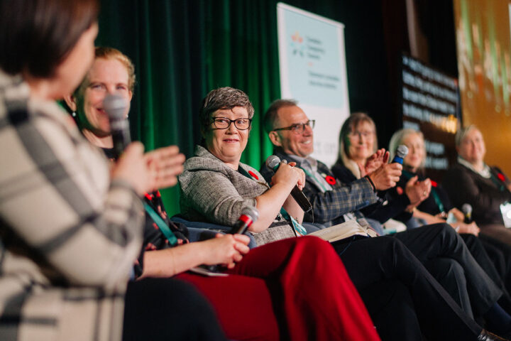 Representatives from the provincial caregiving organizations on stage, with the focus on Julie Bickerstaff from L'Appui pour les proches aidants