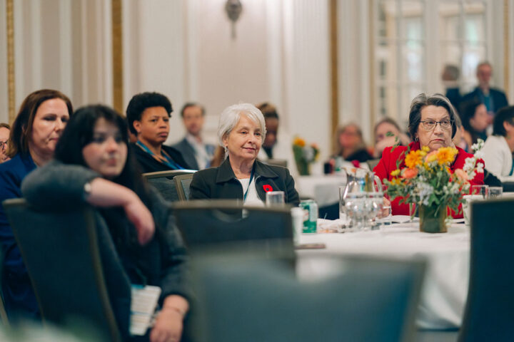 Pamela Barkhouse sits at a round table, with fellow attendees blurred in the background
