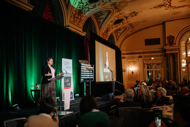 CCCE’s Liv Mendelsohn gives a speech at the podium in front of a crowd of seated attendees.