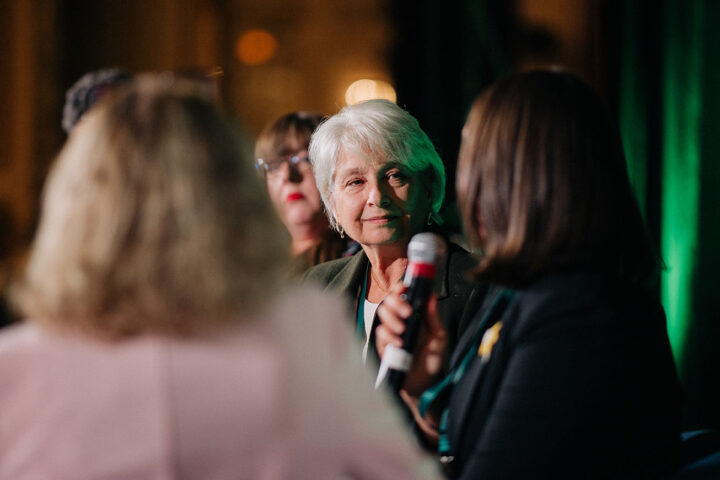 Speakers from the advocacy workshop on stage, with other speakers blurred except for Pamela Barkhouse