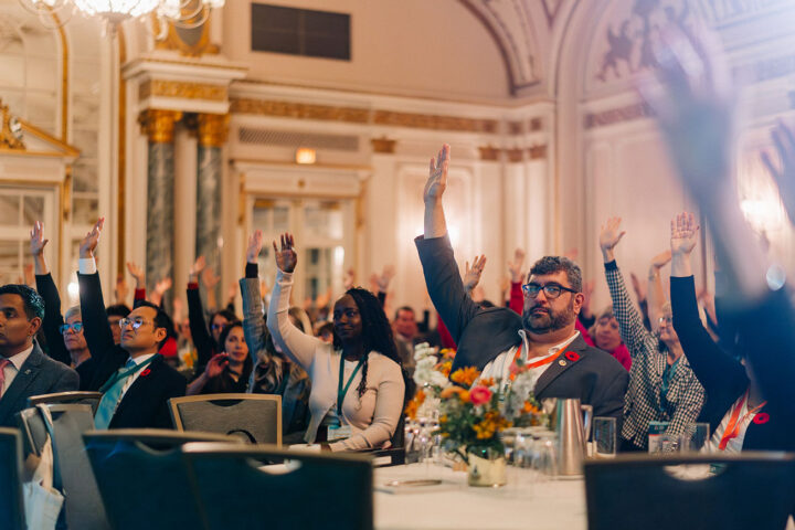 Audience members raising their hands in the air during Arlene Dickinson’s keynote address. CCCE’s director of policy and government relations, James Janeiro, is in focus.