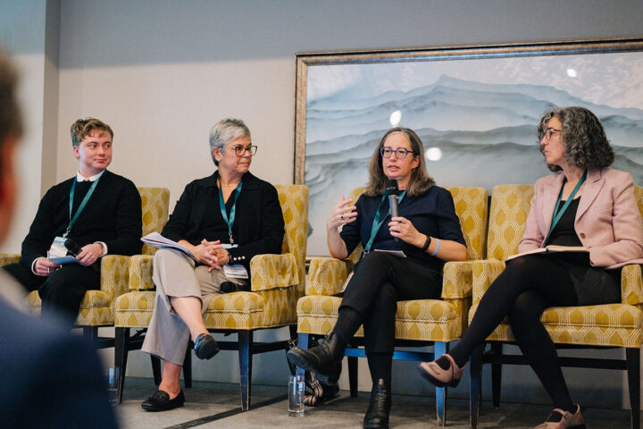 Panelists from the mental health and care panel seated on stage on yellow armchairs, with Dr. Rinat Nissim holding the microphone