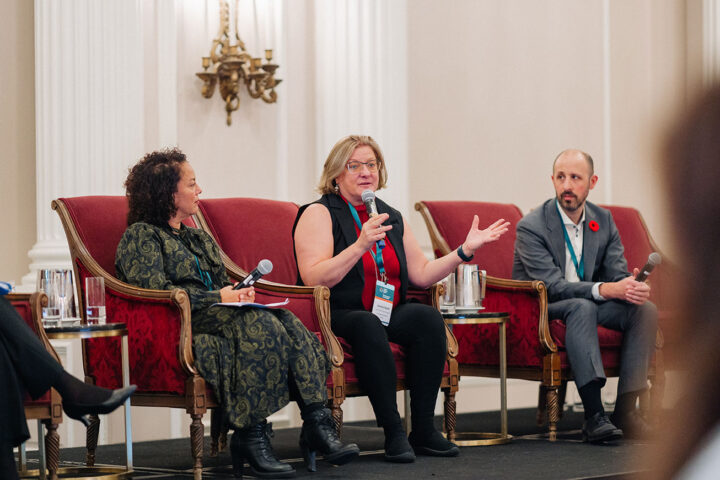 Dr. Janice Keefe speaks at the panel on financial security, with fellow panelists seated on either side.