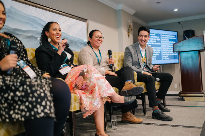 Speakers from the Indigenous Caregiving panel sharing a moment of laughter on stage.