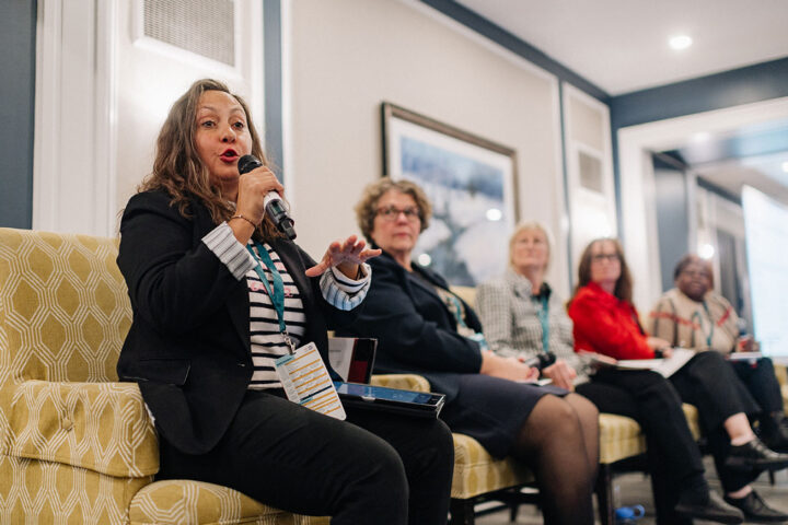 Katrina Love Prescott gestures while speaking at the home care panel, with fellow panelists blurred in the background.