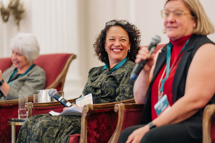 Pascale Pilon seated in a red chair and smiling, with fellow panelists blurred on either side.