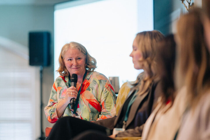 Christa Haanstra holds a microphone while looking at the other speakers on the working caregivers panel.