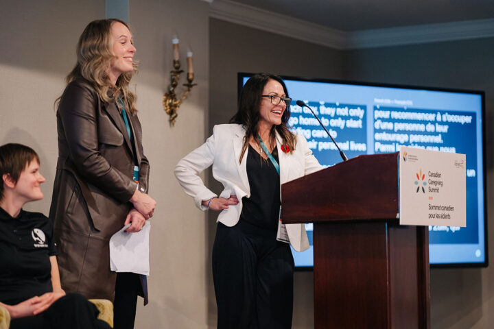 Jill Brooke stands at the podium with one hand propped on her hip during the working caregivers panel. Standing next to her is a fellow panelist.