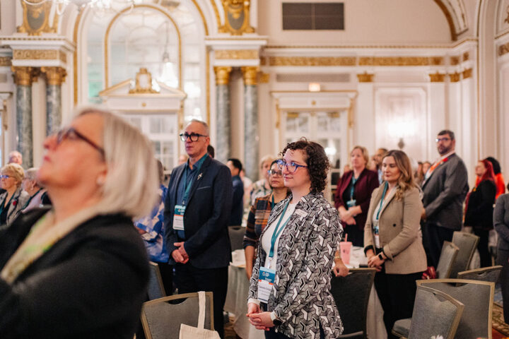 Attendees standing in the main room for the national anthem.