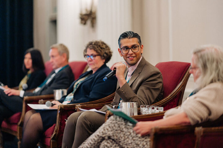 Speakers from the health system reform panel seated in red chairs on stage, with Dr. Kunal Parikh in focus.