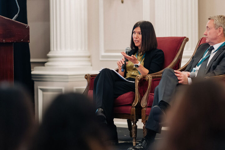 Dr. Kerry Kuluski speaks on the health system reform panel, with blurry silhouettes of attendees in the foreground