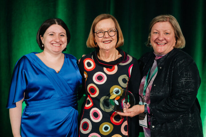 Award recipient Dr. Janice Keefe poses on stage with her award with CCCE's Liv Mendelsohn and Dr. Norah Keating