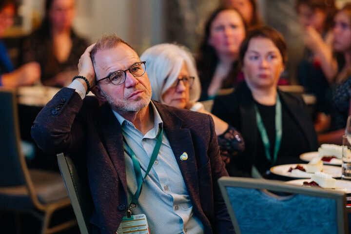 Darrel Gregory from Caregivers Alberta sits with his head propped against his hand as he listens to Donna's story