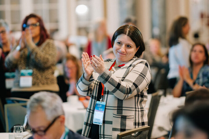 CCCE's Liv Mendelsohn stands up and applauds after Fredrica shares her caregiving story